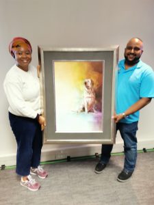 Manny Moodley presenting Dr Gcinashe Nqabeni from Bayer SA with a gift from Retina SA, A painting of a dog in a gold frame