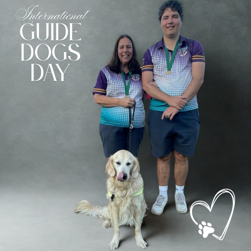 ariza and her son Emil stand in front of a plain backdrop with Dottie her guide dog sitting between them. The text 'International Guide Dogs Day' appears in elegant white lettering on the top left, with a heart and paw print graphic in the bottom right corner.