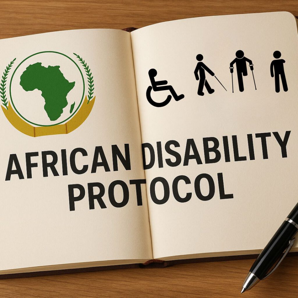 An open notebook on a wooden surface displays the title "African Disability Protocol" in bold black letters. On the left page is a green silhouette of the African continent encircled by a golden emblem with laurel leaves, and on the right is a black disability icons. A black pen lies beside the notebook